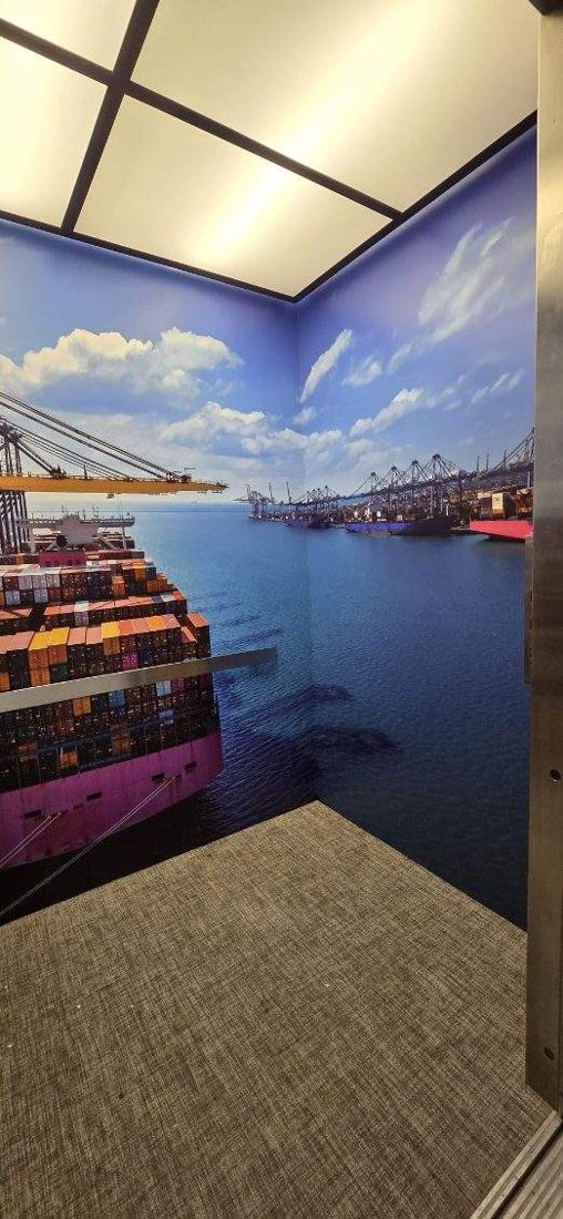 The same elevator cab after the wrap: the corner where a container ship meets open harbor water, wrapping both walls.