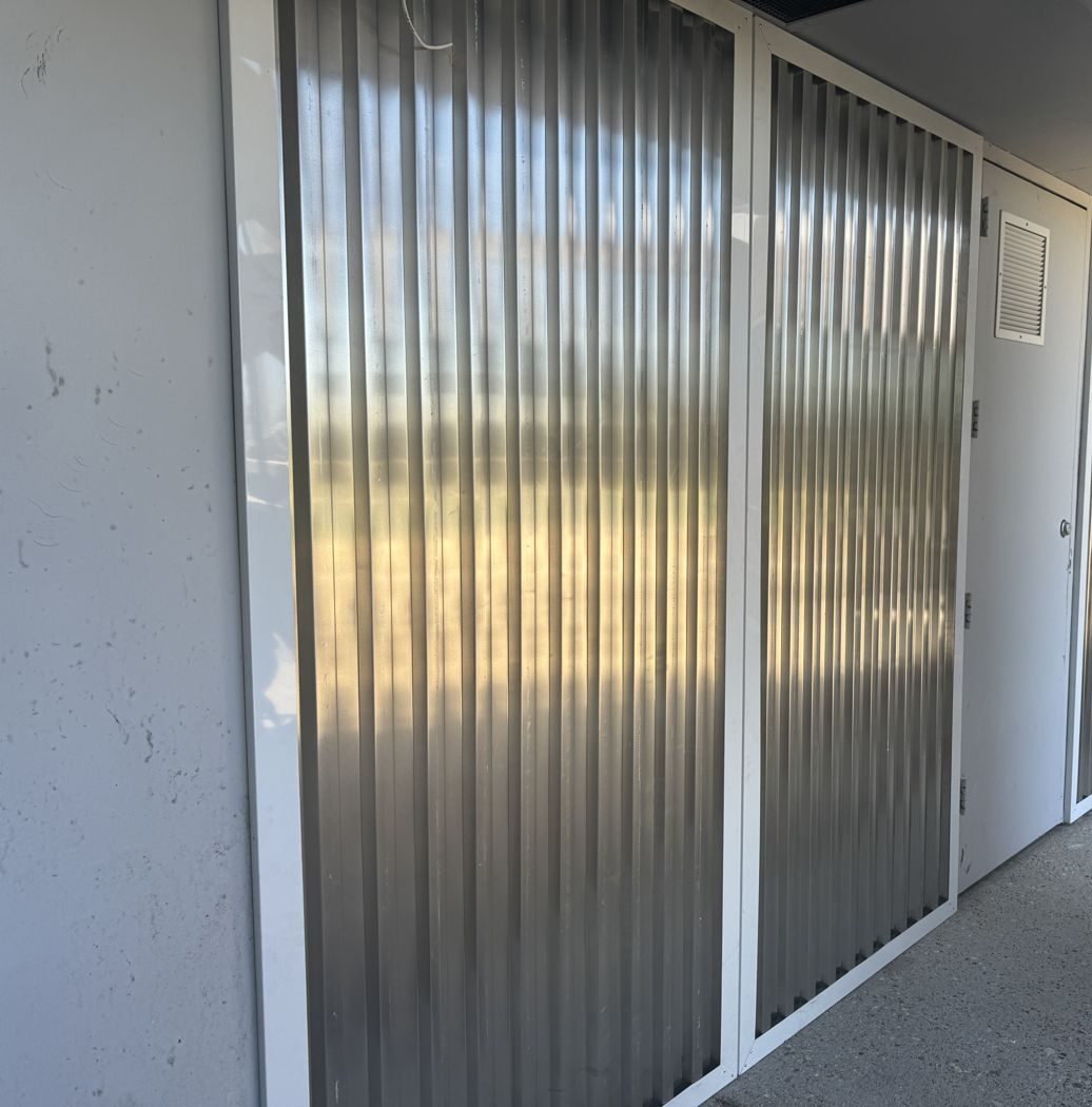 Exterior service entry clad in corrugated metal panels, echoing shipping container walls.