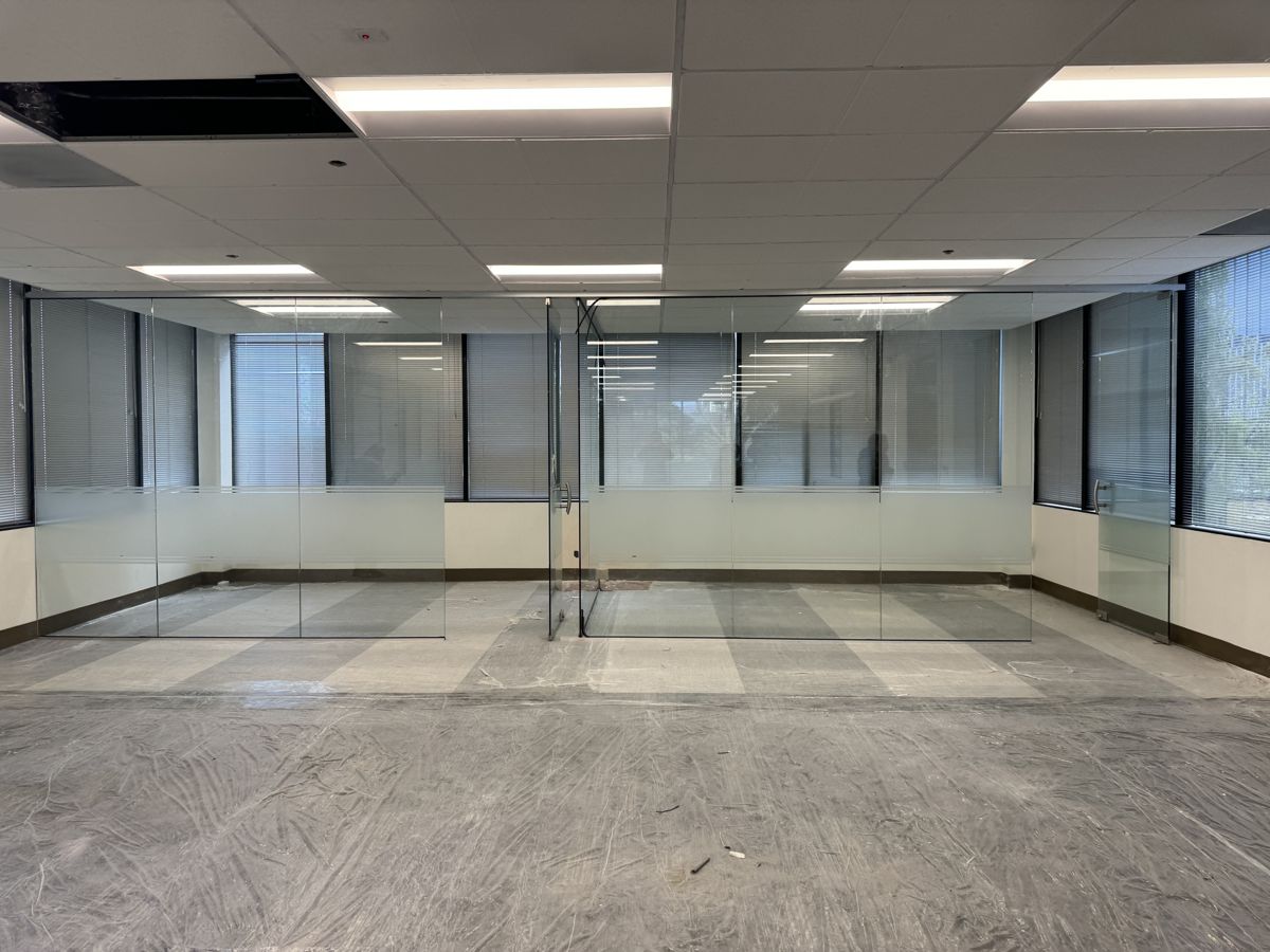 The office glass partitions before graphics: clear glass walls with a plain frosted band, empty office floor.