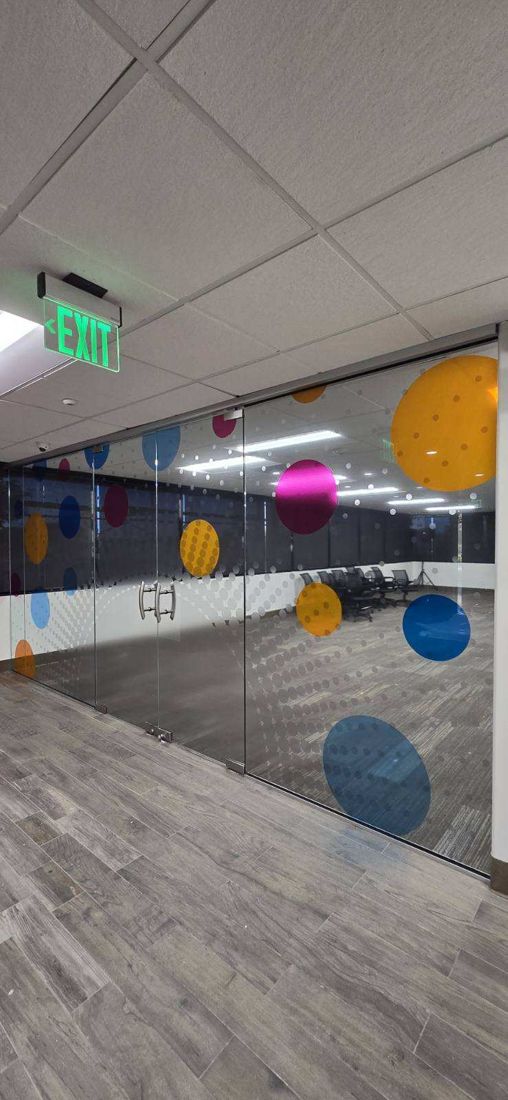 A glass corridor after installation: colored map-point dots running down the frosted glass wall.