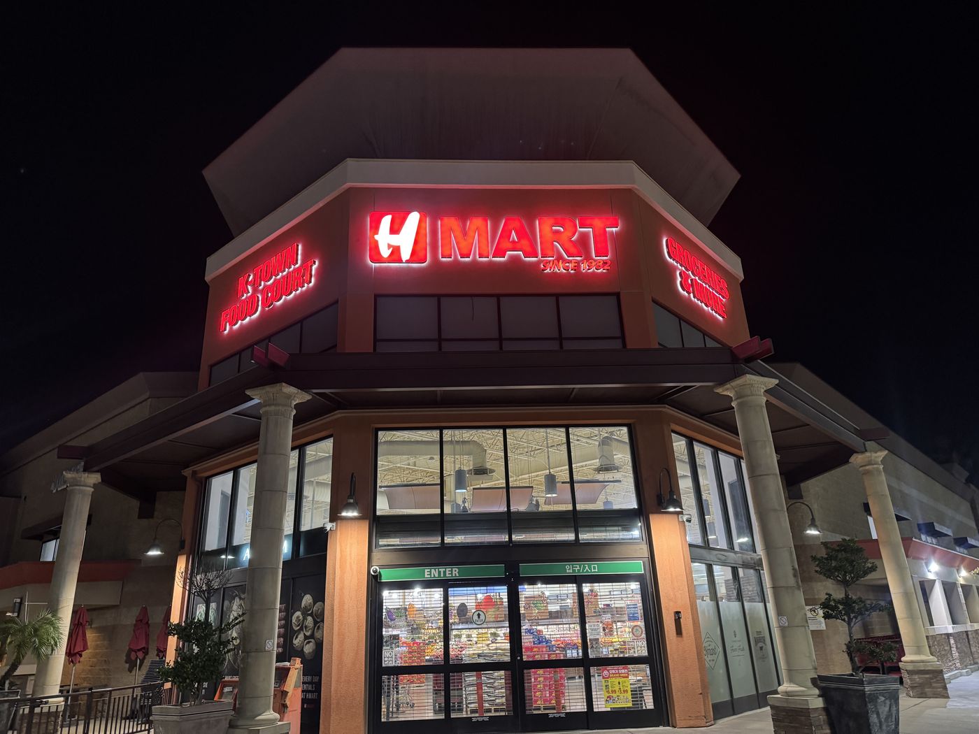 The same H Mart Buena Park tower after renewal at night: H MART, K-Town Food Court, and Groceries and More all glowing in deep, even red.