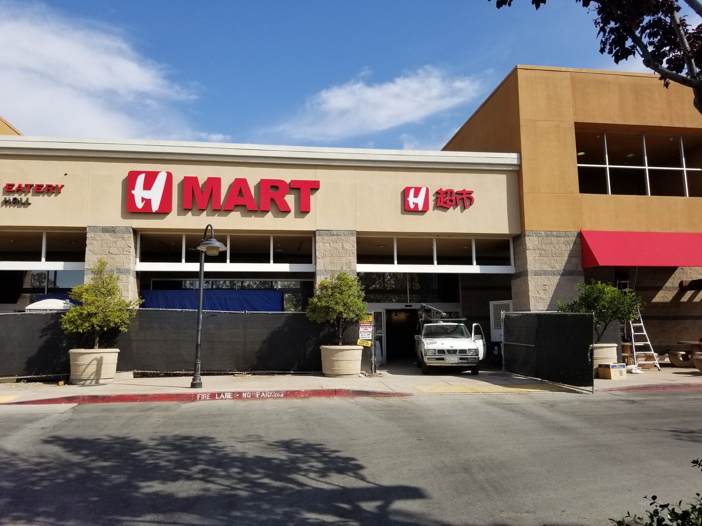 H Mart San Jose in 2017 during construction: vivid red H MART and Chinese-character signs above barricade fencing on install day.