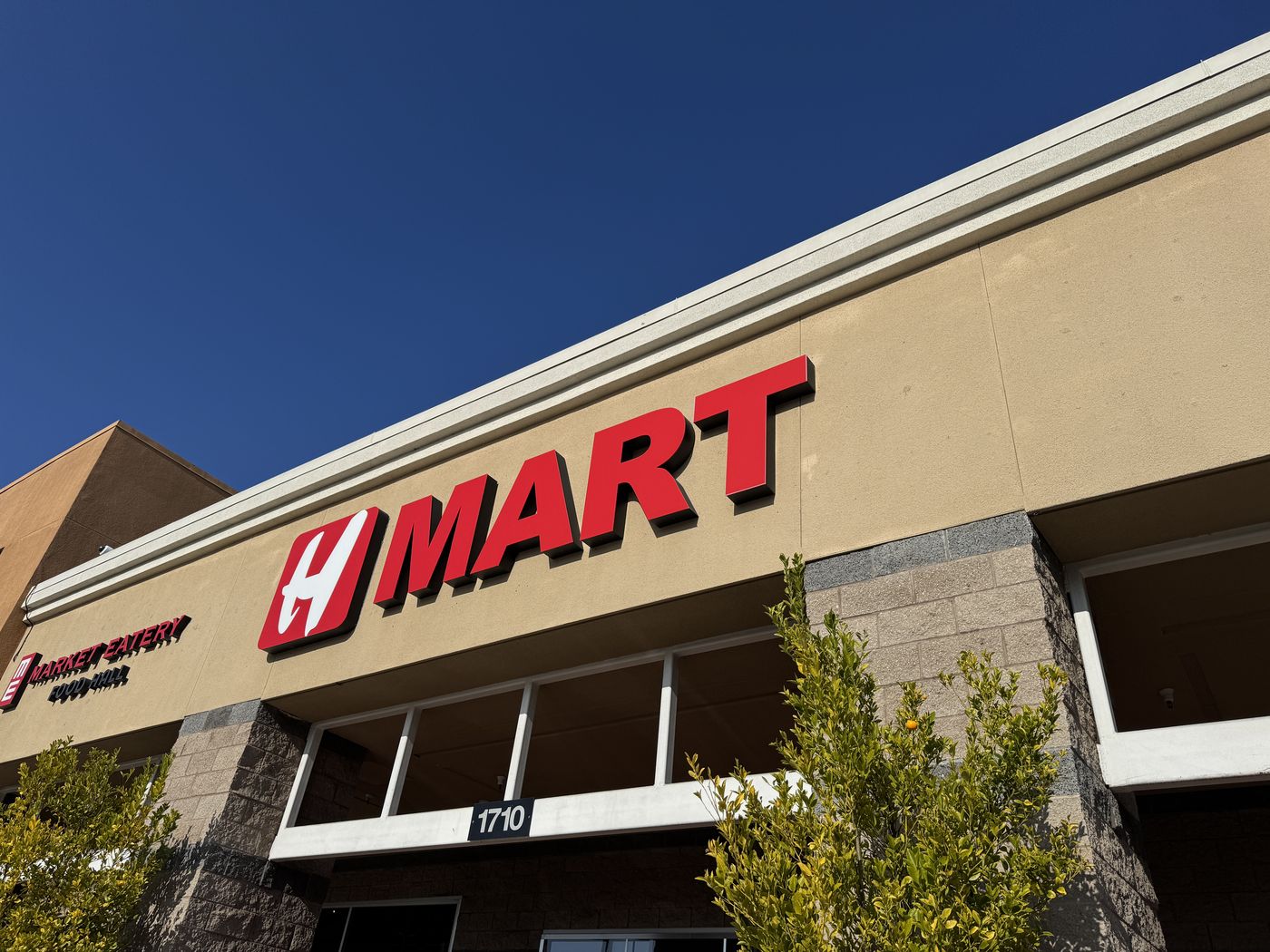 The same H MART sign in 2026 after refacing by DT Signs: deep saturated red against a clear blue sky.