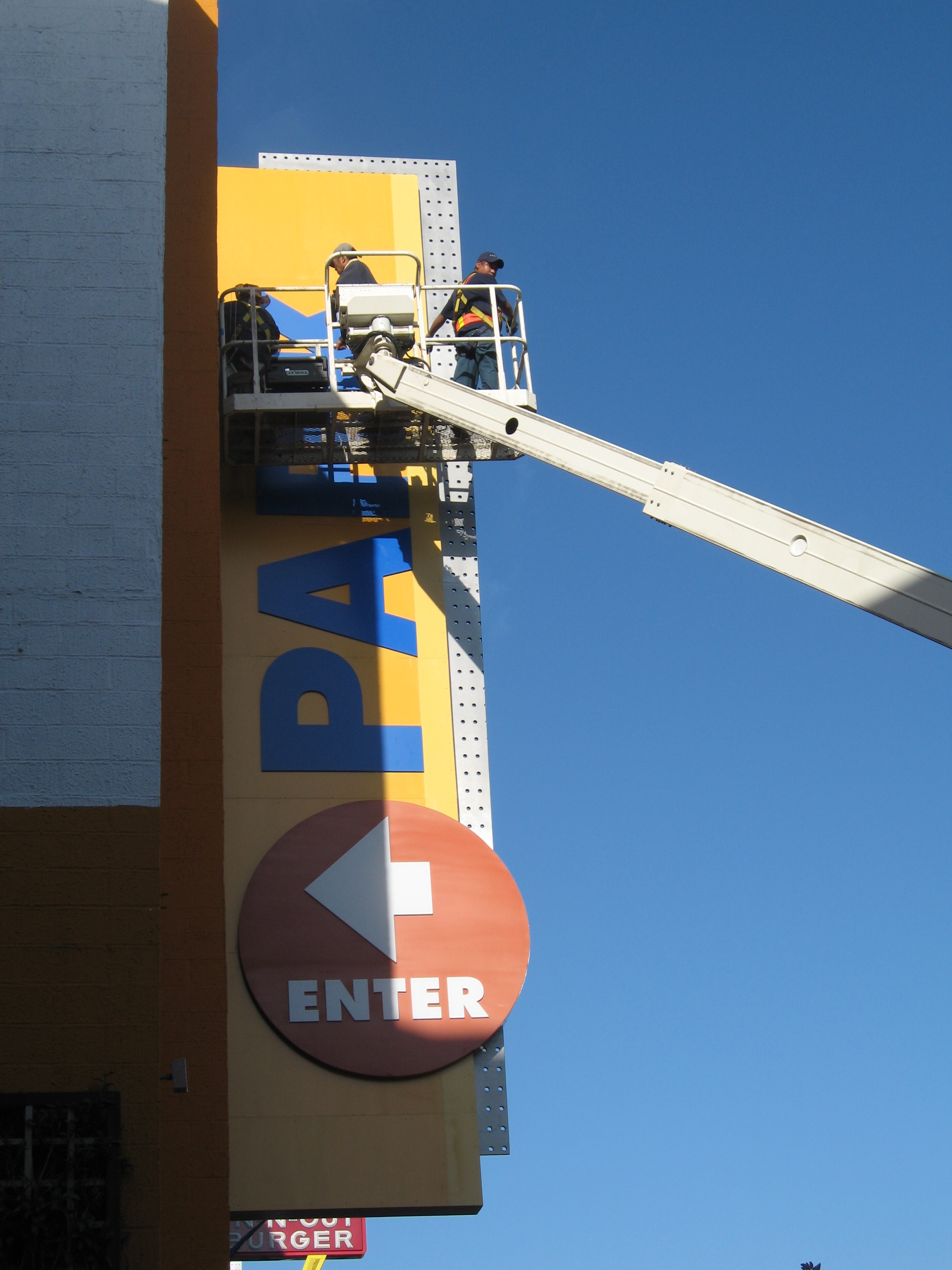 Round ENTER entry sign and PARK letters being installed from a lift