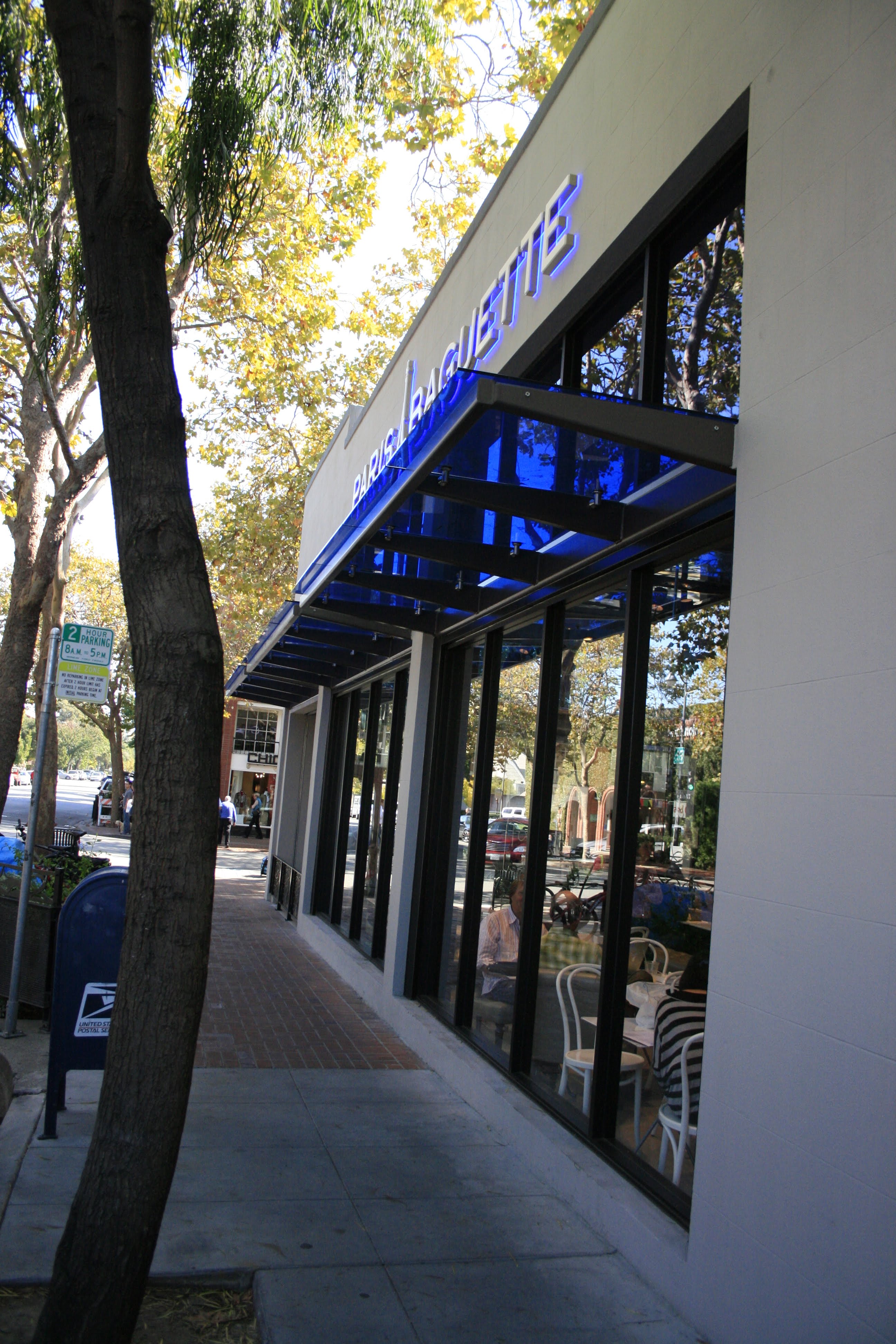 Blue glass canopy detail along the Paris Baguette storefront