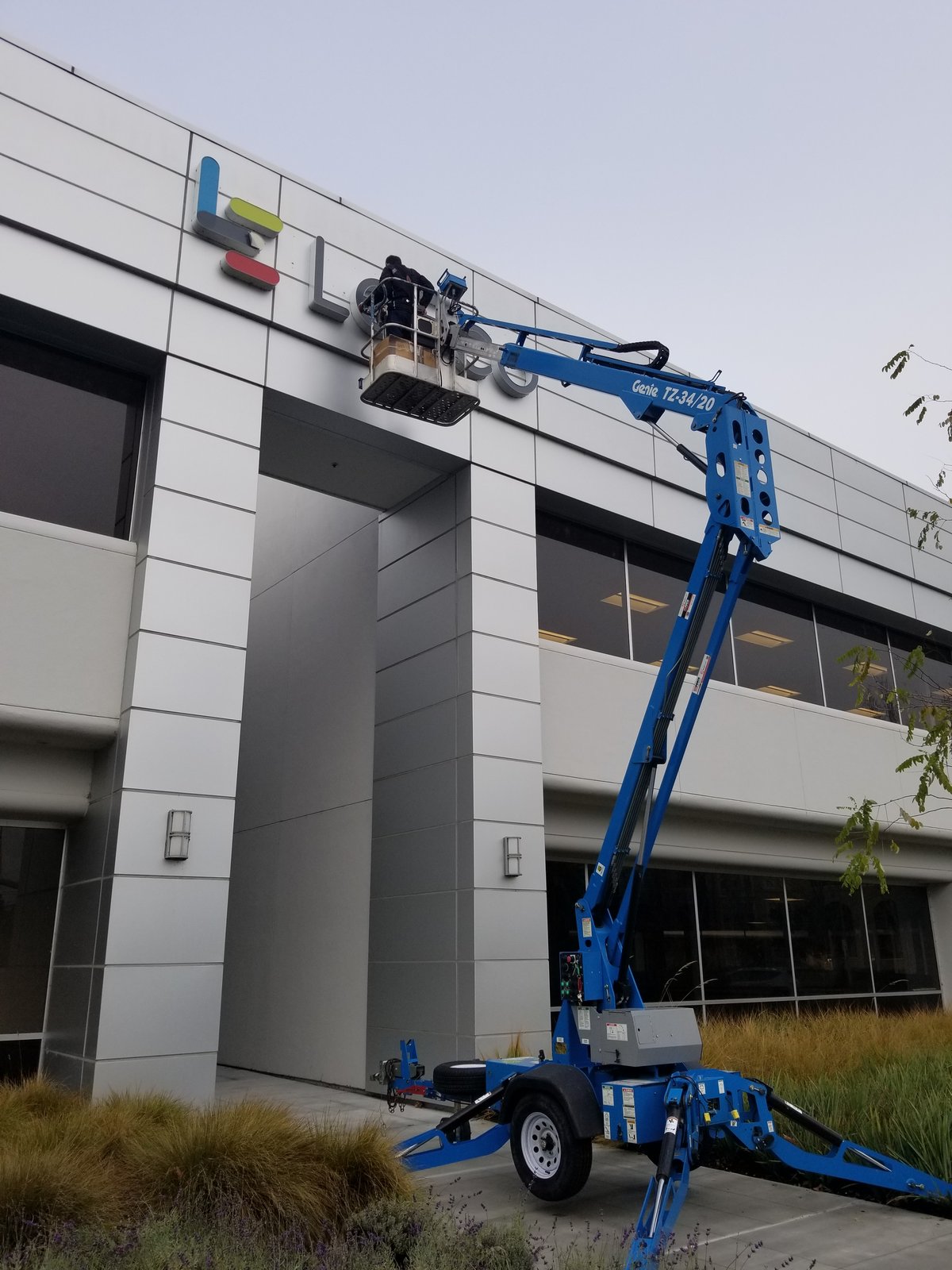 Genie lift installing channel letters on a building facade
