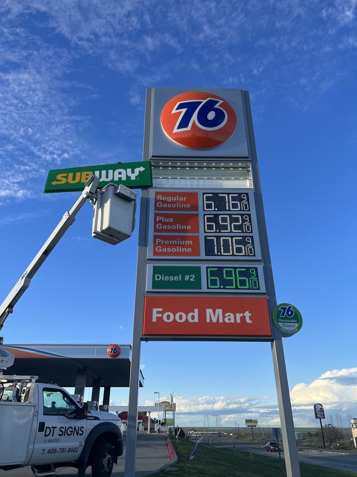 Bucket truck at a 76 gas station price pylon