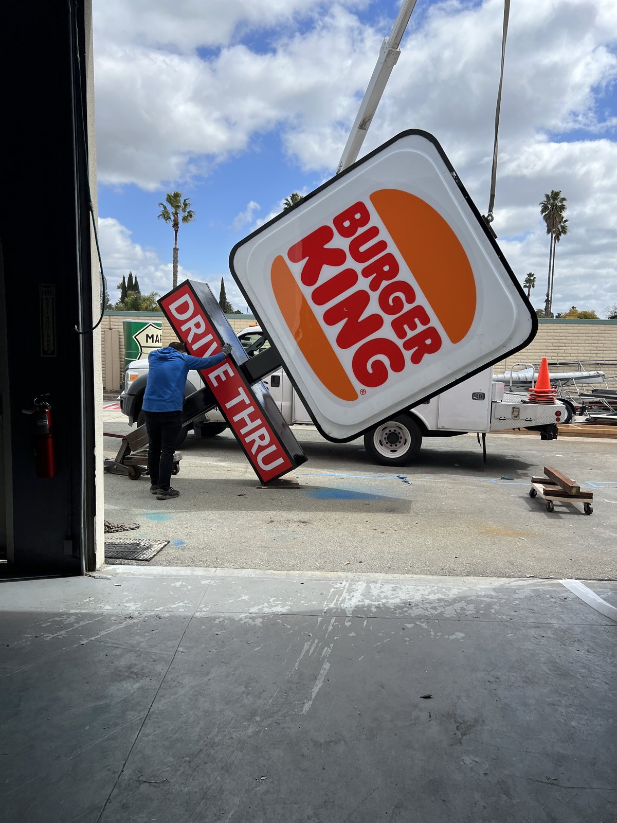 Crane lifting a Burger King pole sign at the shop