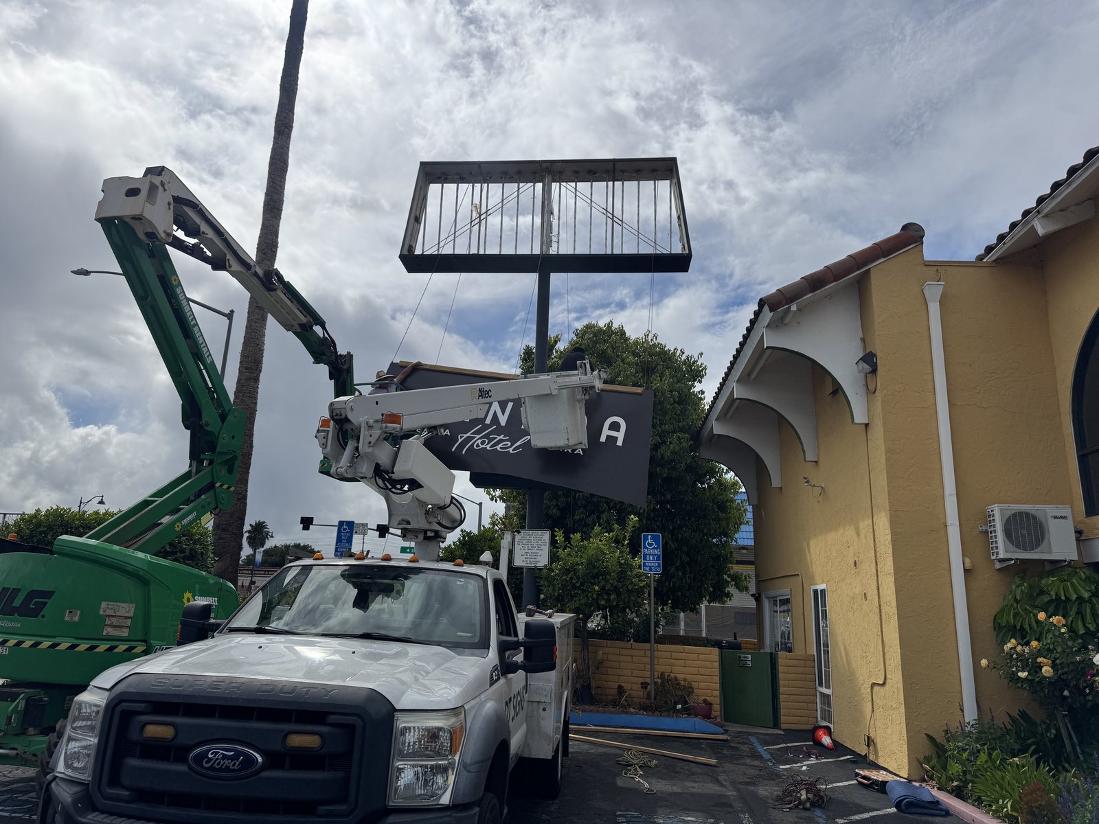 Boom lift and bucket truck installing a hotel pylon sign