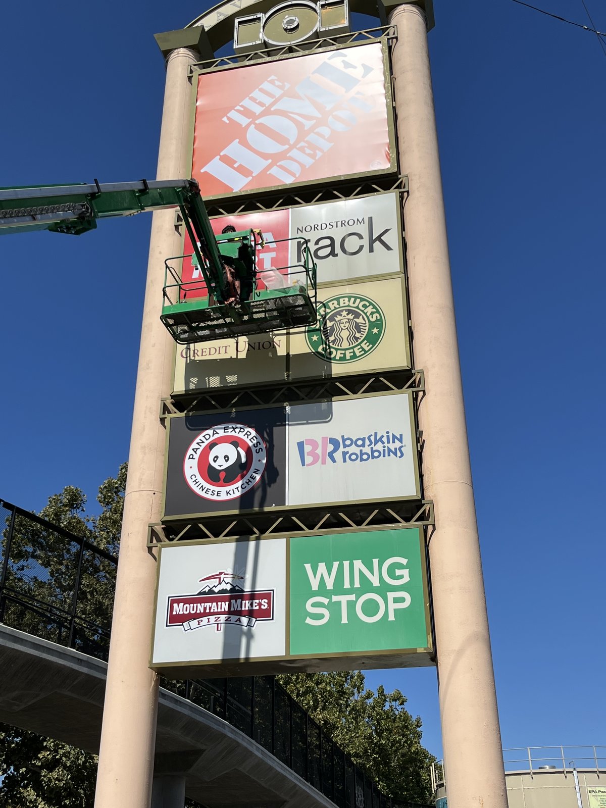Boom lift installing tenant panels on a shopping-center pylon