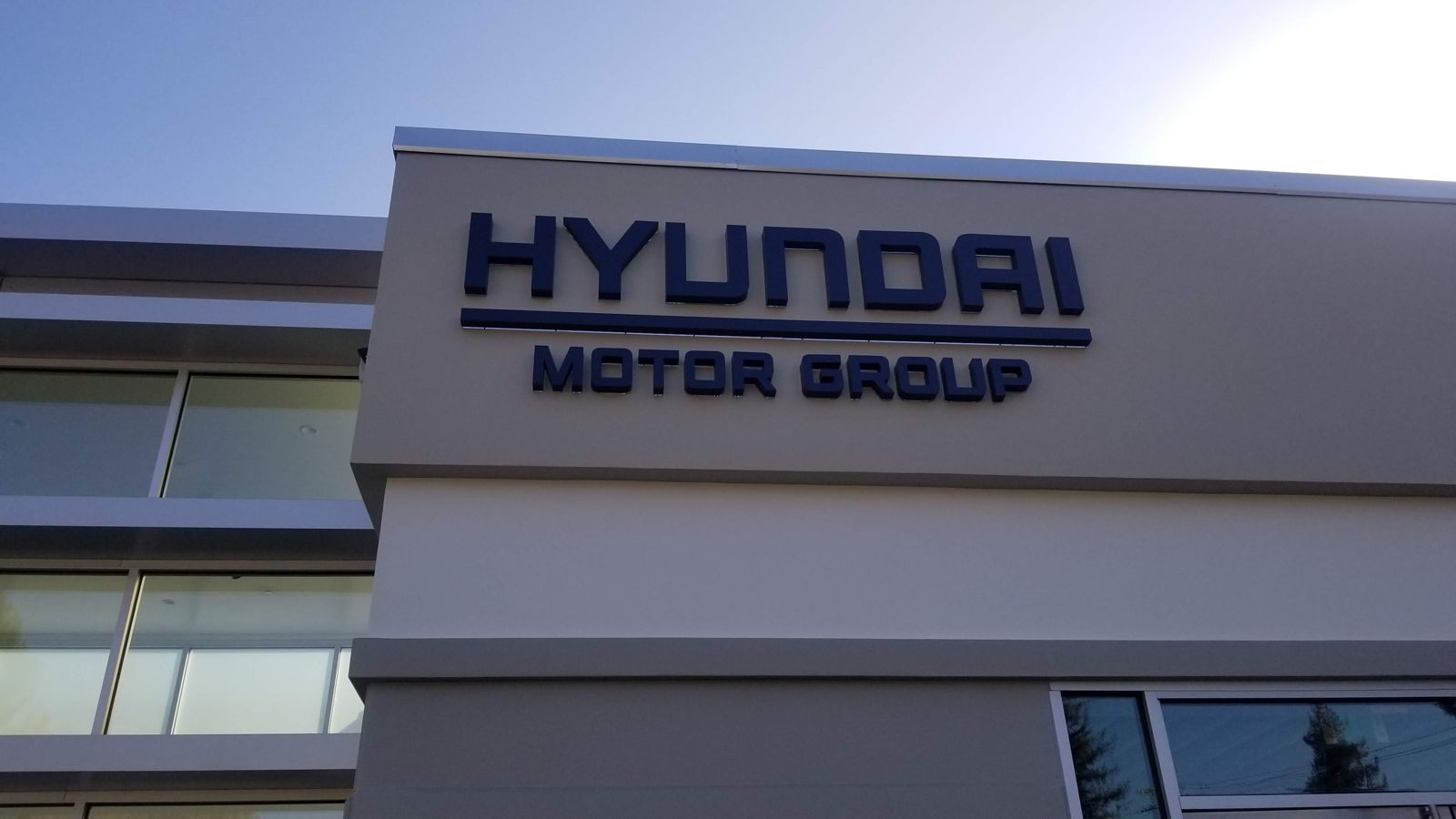 Hyundai Motor Group letters in dark dimensional lettering on the facade of the Mountain View innovation center, with glass curtain-wall entry to the left.