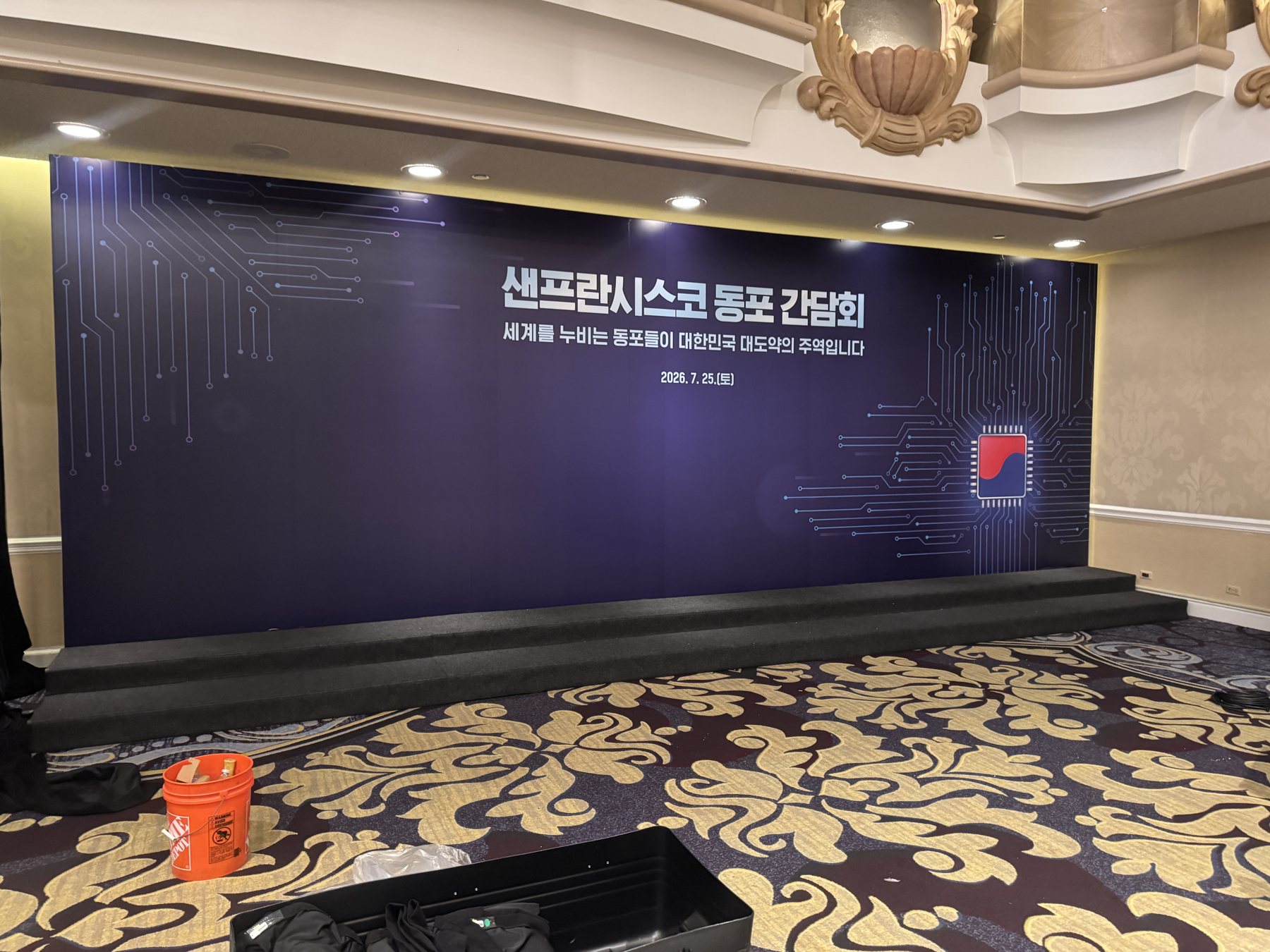 The finished stage backdrop wall spanning the ballroom stage, its dark graphic seamless from edge to edge.