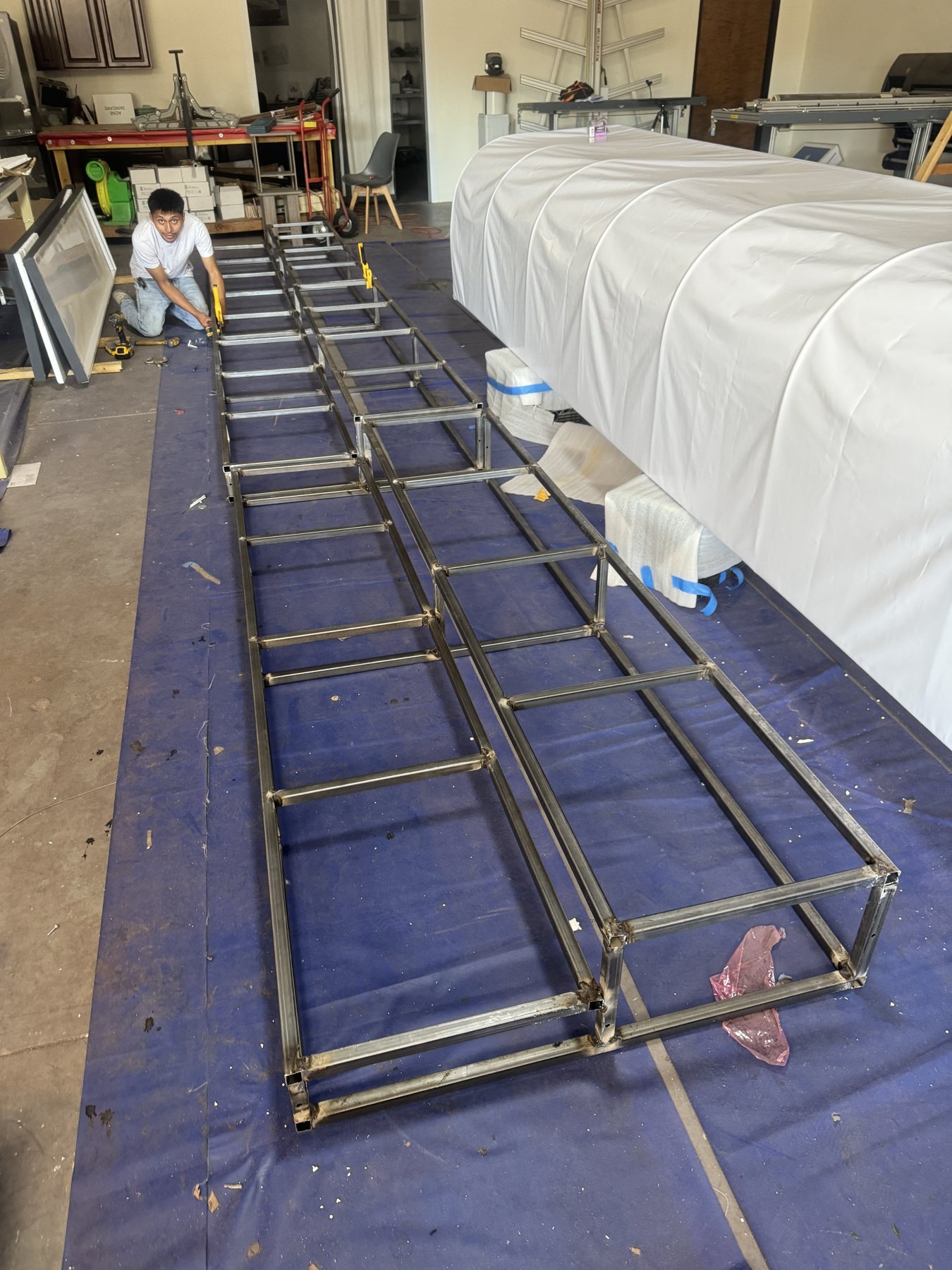 A long welded steel frame for an event wall laid out on the shop floor, ready to transport.