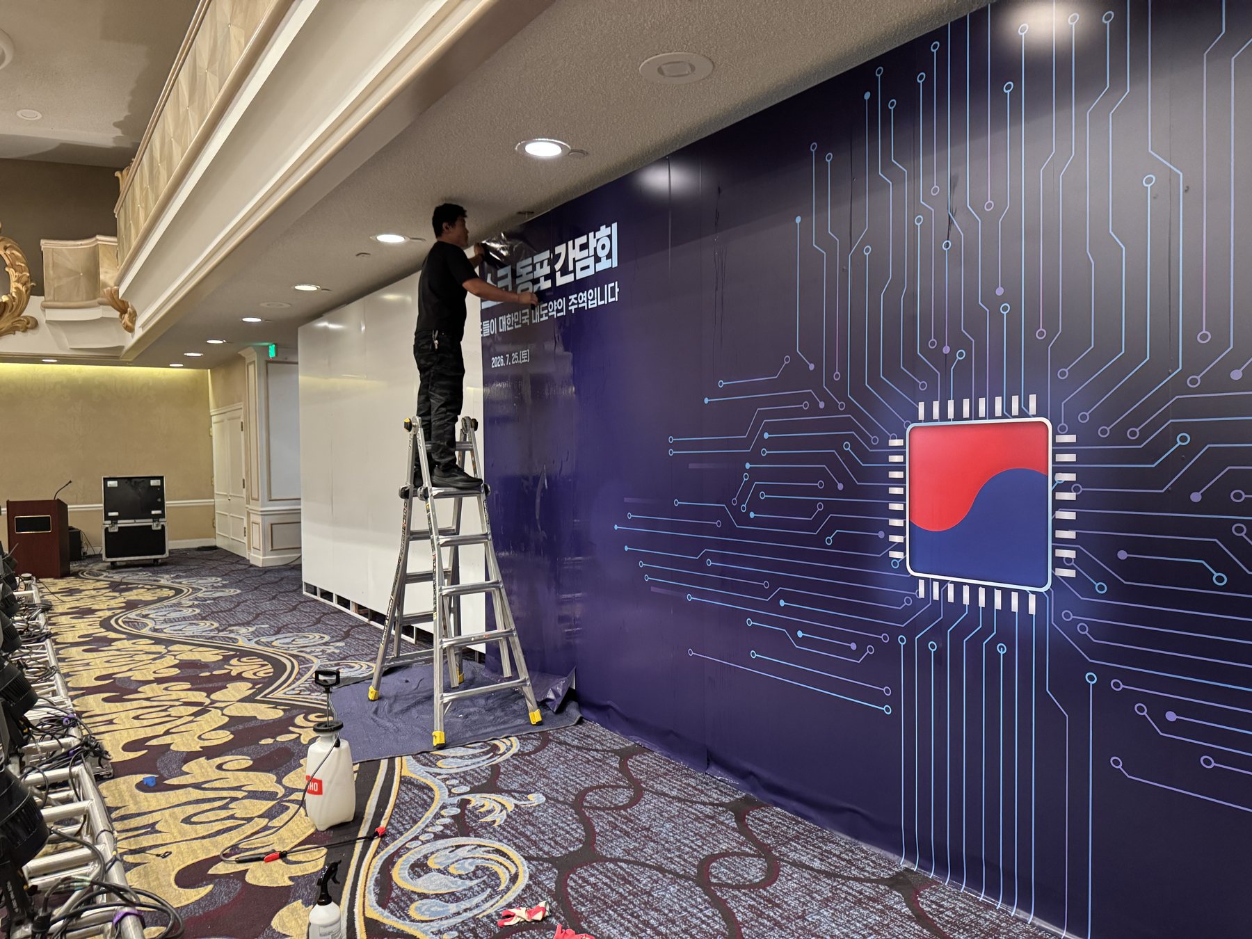 An installer on a ladder applying the printed wallpaper graphic across the ACM wall.