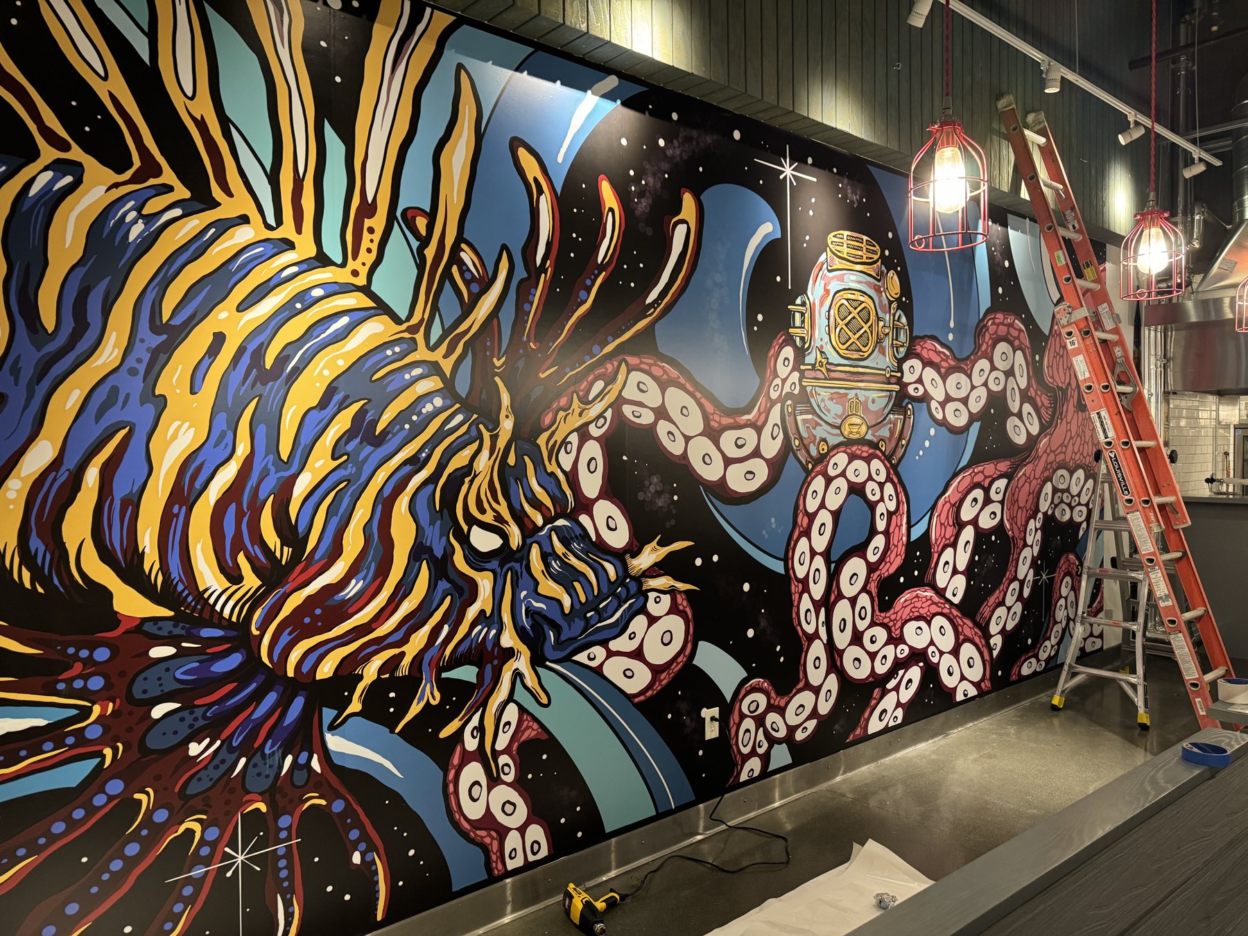 A vivid octopus-and-diver artwork printed as custom wallpaper, covering a restaurant wall edge to edge.